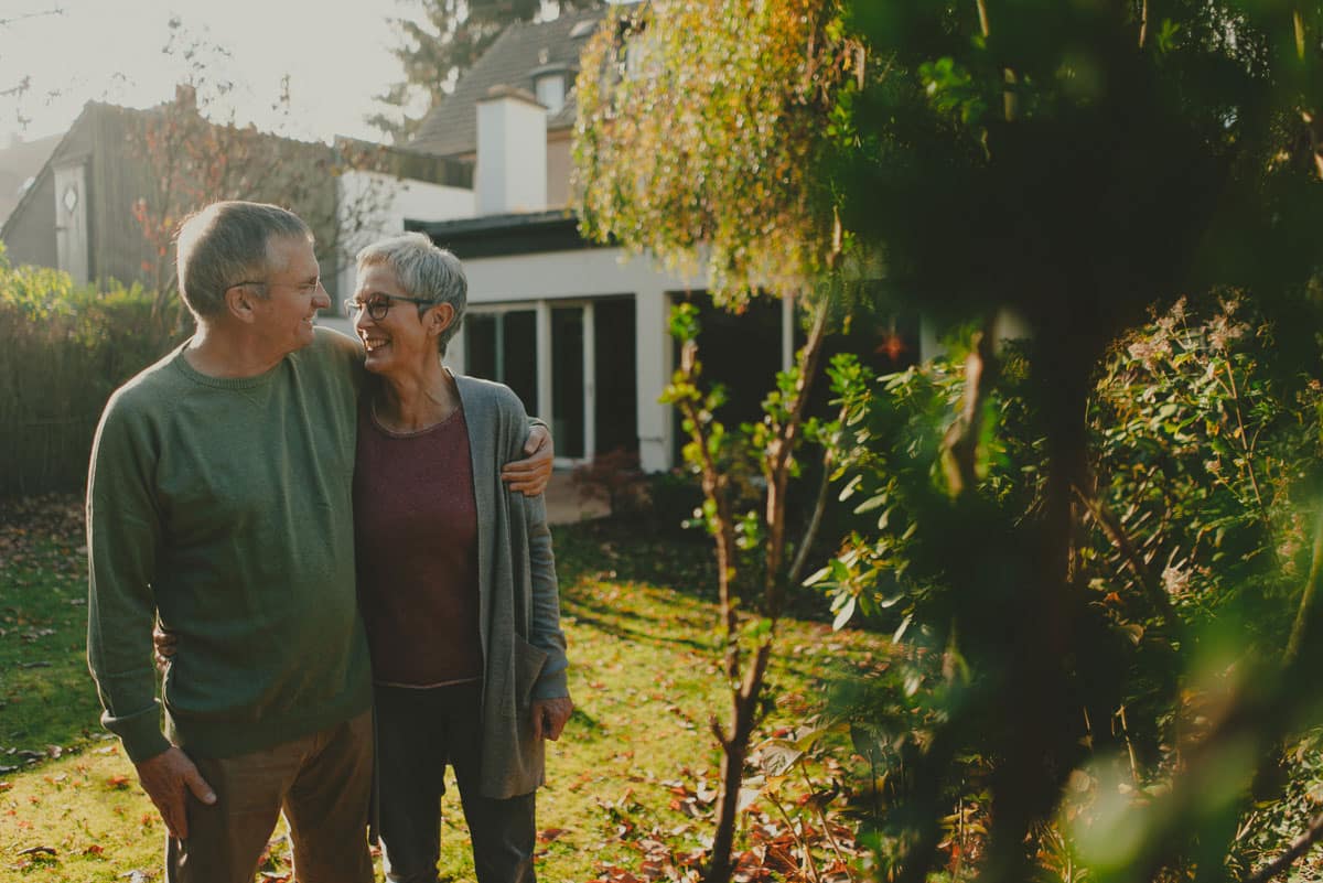 Glückliches Ehepaar Arm in Arm auf ihrem Grundstück mit Immobilie in cottbus